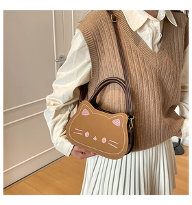 Mini sac à main en forme de chat avec bandoulière porté par un mannequin en tons chauds