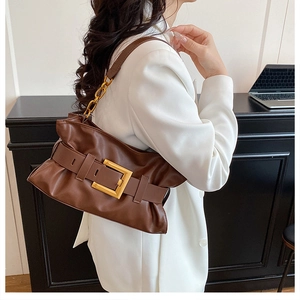 Détail du sac cabas en cuir marron avec grande boucle dorée et côtés plissés élégants