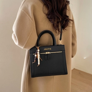 Sac bandoulière minimaliste en cuir noir avec détails dorés et pendentif en perles