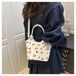 Detail of white PU leather crossbody bag with cherry print on a denim dress model