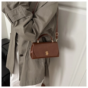Brown vintage leather crossbody bag featuring a golden twist lock on a wool coat outfit
