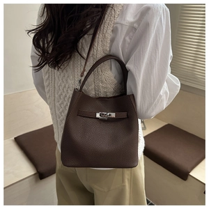 Detailed view of dark brown pebbled leather texture and silver twist lock on bucket bag