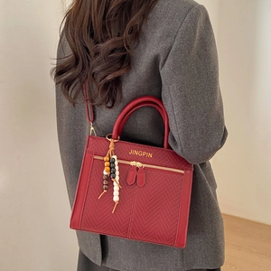 Sac bandoulière rouge à chevrons avec lettrage doré et pendentif gland en perles