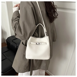 Detail of white lychee leather bucket bag with metal bar lock shown on female model