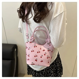Detailed shot of pink patent leather cherry bucket bag with silver hardware and shoulder strap