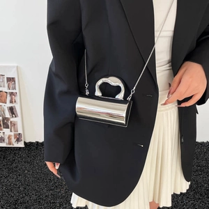 Silver metallic cylindrical crossbody bag with wavy handle and chain strap on model