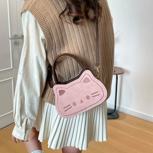 Sac bandoulière chat rose avec broderies et poignée marron porté par un mannequin