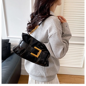 Détail du sac bandoulière en cuir souple noir avec grande boucle dorée et bandoulière chaîne