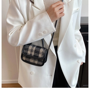 Detail of a mini plaid tweed crossbody bag with black leather trim on a white blazer