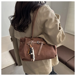 Detailansicht der braunen Wildleder-Tragetasche mit Schnalle und Vintage-Perlenanhänger-Zubehör