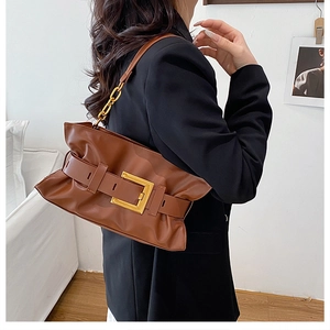 Détail du sac bandoulière en cuir marron avec grande boucle dorée et bandoulière chaîne