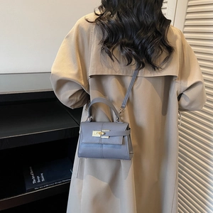 Chic blue textured leather mini crossbody bag with gold lock on beige trench coat