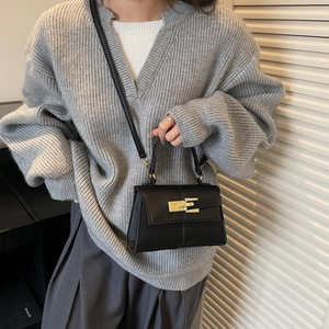 Minimalist black leather crossbody mini Kelly bag with gold lock shown on a model