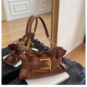 Détail d'un sac à bandoulière marron plissé avec boucle dorée et chaîne épaisse
