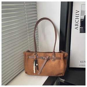 Gros plan d'un sac cabas en daim marron avec sangle en cuir et breloque perlée