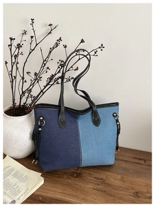 Détail du sac fourre-tout en denim bicolore avec lanières en cuir et cordons latéraux