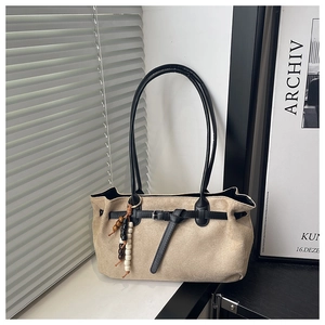 Détail du sac cabas en daim beige avec garnitures en cuir noir et breloque en perles rétro