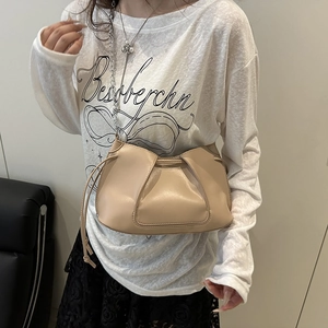Elegante borsa a tracolla beige a pieghe con catena in metallo su una modella