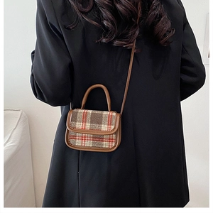 Close-up of a mini plaid crossbody bag with brown leather trim on a black blazer