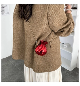 Detail view of the red money bag shaped acrylic clutch worn as a stylish crossbody bag