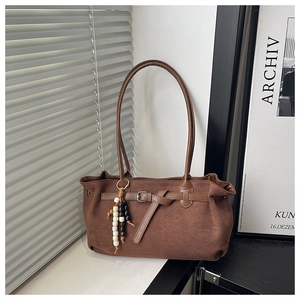 Détail du sac cabas en daim marron foncé avec charme perlé rétro et texture mate fine