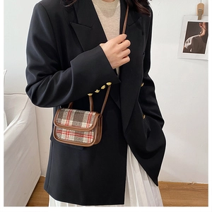 Detail of a mini crossbody bag featuring a classic red plaid pattern and leather trim