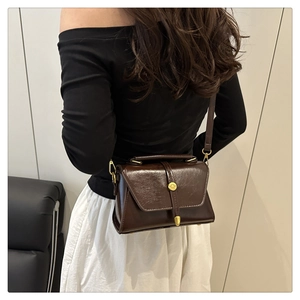 Detail view of the deep brown vintage crossbody bag with gold circular metal buckle