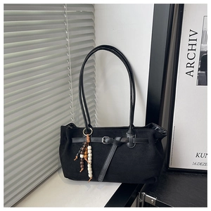 Détail d'un sac à main vintage en daim noir avec bandoulière et pendentif en perles