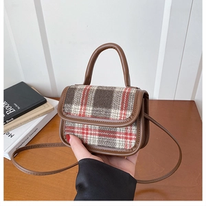 Close-up of red and black plaid tweed crossbody bag with brown leather handle details