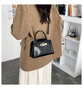 Sac à main trapèze noir brillant avec fermoir tournant doré et bandoulière amovible