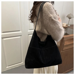 Vue latérale d'un grand sac fourre-tout noir minimaliste porté à l'épaule au quotidien