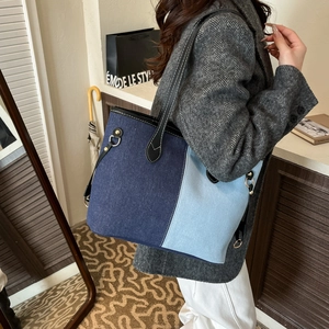 Minimalist denim tote bag with two-tone patchwork and black leather straps in use