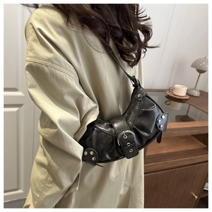 Detail of black semi-circle underarm bag with silver buckles and studs in a lifestyle setting