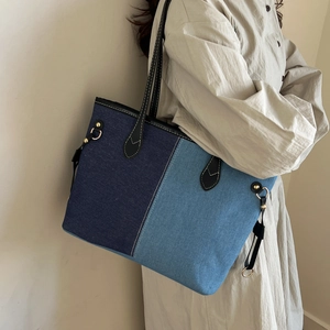 Blue denim patchwork tote bag with black leather strap and gold buckle detail