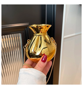 Macro detail of a shiny gold lucky bag shaped mini handbag with mirror finish and chain