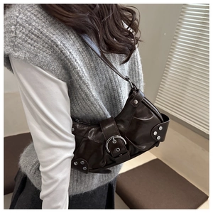 Detail view of a vintage dark brown shoulder bag with silver buckle and rivet accents