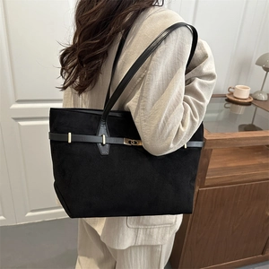 Schwarze Wildleder-Tote-Bag im Retro-Stil mit Metallschnalle am Modell im modernen Haus