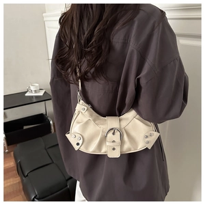Detail of cream hobo bag featuring silver buckle and ruched leather on model shoulder