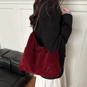 Sac fourre-tout minimaliste bordeaux en daim mat porté par un mannequin pour 2026