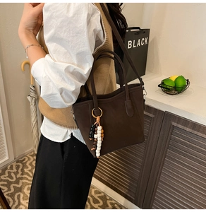Brown suede tote bag with beaded charm detail shown on model in cozy home setting