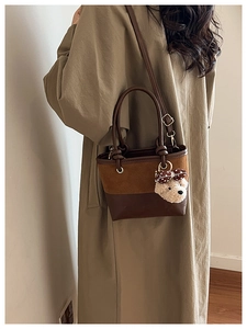 Detail view of contrast textures on a stylish bucket bag with a cute teddy bear charm