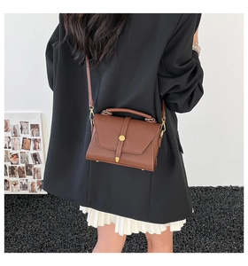 Close-up of brown litchi pattern leather bag with gold buckle on a stylish model