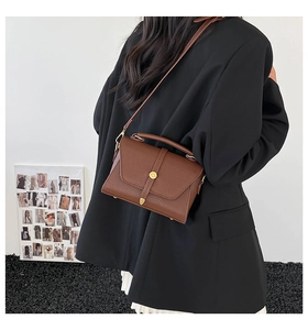 Detail of vintage brown pebble leather crossbody bag with gold buckle and top handle