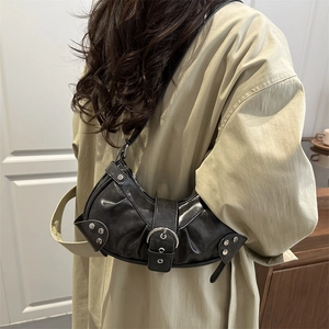 Minimalist black crescent shoulder bag with silver buckle and rivets on beige trench coat