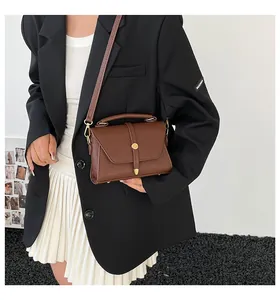 Deep brown pebble leather crossbody bag with gold hardware shown on a model