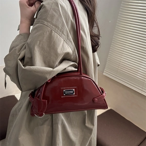 Deep red patent leather underarm shoulder bag with silver metal plaque on model