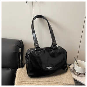 Detail einer glänzenden schwarzen Lackledertasche mit silbernen Ringen auf weichem Stoff
