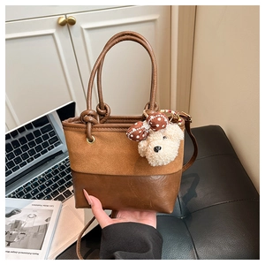 Close-up of brown patchwork bucket bag with cute plush bear charm and long strap