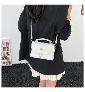 Rear view of model wearing a white pebbled leather crossbody bag with gold round buckle