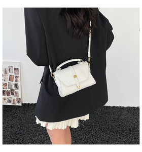 White lychee pattern crossbody bag with gold lock shown on a model in a black suit